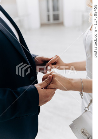 Bride and groom with bands holding hands and touching during their wedding ceremony Bride and groom with bands holding hands and touching during their wedding ceremony 117308459