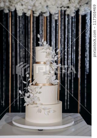 Wedding setup with three-tier white cake with floral accents. Wedding inspiration, luxury events Wedding setup with three-tier white cake with floral accents. Wedding inspiration, luxury events 117308469