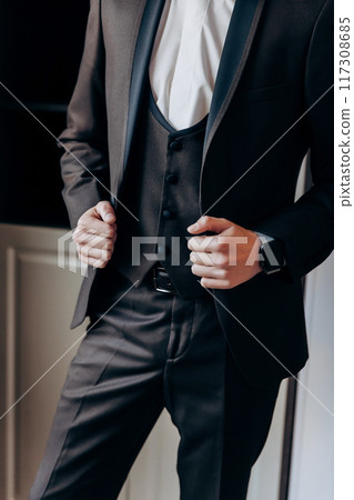 Businessman adjusting his suit jacket, emphasizing professionalism and attention to detail in office Businessman adjusting his suit jacket, emphasizing professionalism and attention to detail in office 117308685