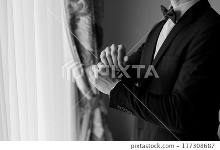 Businessman adjusting his suit jacket, emphasizing professionalism and attention to detail in office Businessman adjusting his suit jacket, emphasizing professionalism and attention to detail in office 117308687