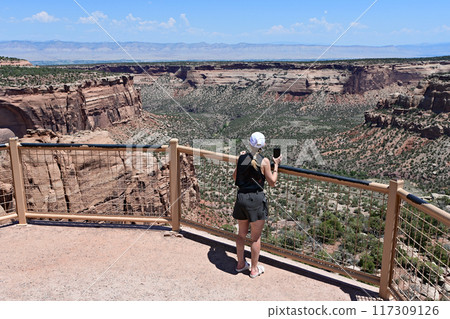 Woman photographing and enjoying scenery of Colorado National Monument. 117309126