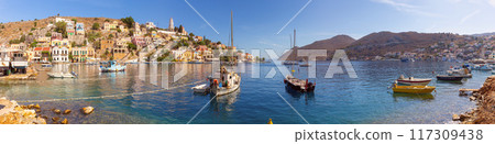Colourful house facades and fishing boats in the bay of Symi village at sunset. Colourful house facades and fishing boats in the bay of Symi village at sunset. 117309438