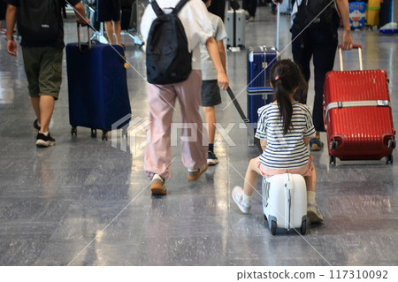 Passenger carrying a child in a suitcase in the international departure lobby 117310092