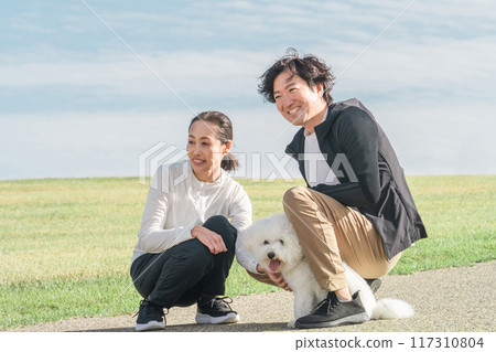 Dog loving couple/family/family (middle-aged/middle) walking their dog in the park Dog loving couple/family/family (middle-aged/middle) walking their dog in the park 117310804