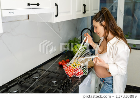 Pregnant woman inspecting vegetables in kitchen 117310899