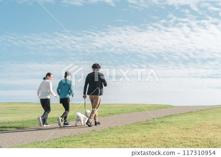 一個令人耳目一新的家庭/父母和孩子在公園裡遛狗、運動、訓練和做有氧運動，欣賞藍天的景色 117310954