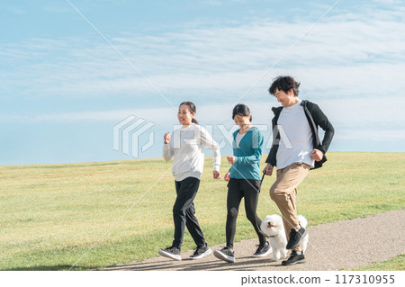 一個令人耳目一新的家庭/父母和孩子在公園裡遛狗、運動、訓練和做有氧運動，欣賞藍天的景色 117310955