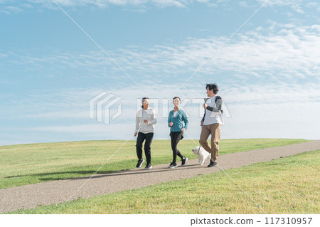 一個令人耳目一新的家庭/父母和孩子在公園裡遛狗、運動、訓練和做有氧運動，欣賞藍天的景色 117310957
