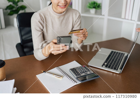 Young woman make a purchase on the Internet on the laptop and mobile with credit card 117310980