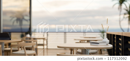 A space for displaying products on a wooden table on a restaurant outdoor terrace with a sea view. A space for displaying products on a wooden table on a restaurant outdoor terrace with a sea view. 117312092