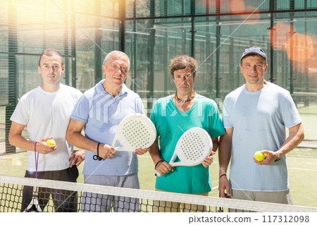 Group of men posing on padel tennis court Group of men posing on padel tennis court 117312098