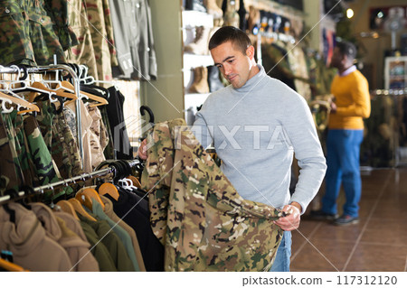 Man choosing camouflage outwear in military store 117312120