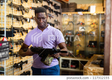 Portrait of african american man in gun shop showing rifle Portrait of african american man in gun shop showing rifle 117312155