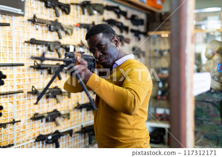 Customer man is choosing air-powered gun in army market closeup Customer man is choosing air-powered gun in army market closeup 117312171