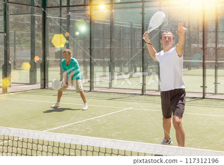 Padel game - man with partners plays on court Padel game - man with partners plays on court 117312196