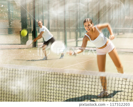 Young woman and man playing doubles padel Young woman and man playing doubles padel 117312203