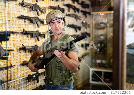 Guy in military equipment with weapon in army shop 117312205