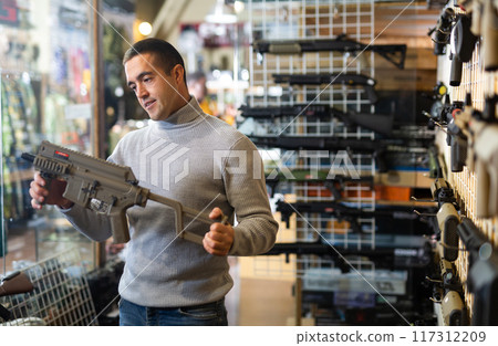 Man chooses semi-automatic pneumatic assault rifle at gun store Man chooses semi-automatic pneumatic assault rifle at gun store 117312209