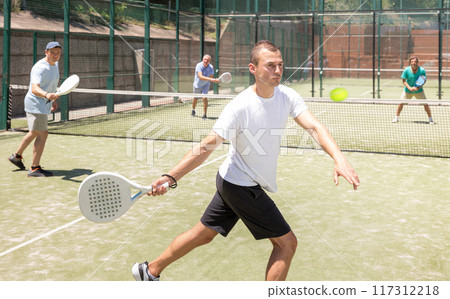 Adult and young men playing padel against two men 117312218