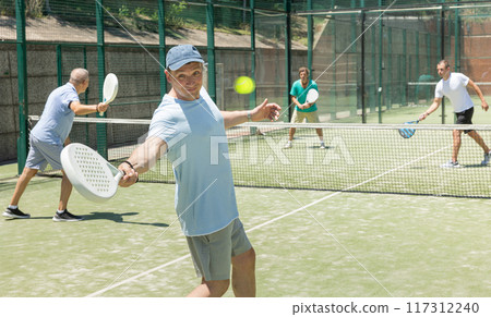 Adult and elderly men playing padel against two men 117312240