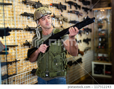 Guy in military equipment with weapon in army shop 117312243