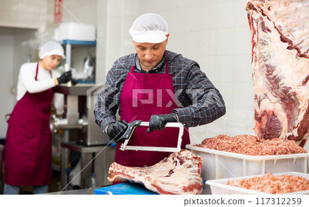 Butcher sawing veal ribs according to customer order Butcher sawing veal ribs according to customer order 117312259