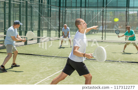 Padel game - man with partners plays on court 117312277
