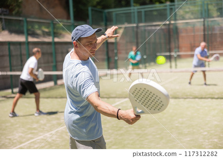 Padel game - man with partners plays on court Padel game - man with partners plays on court 117312282