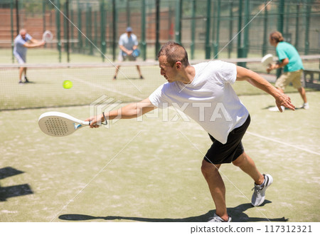 Adult and young men playing padel against two men Adult and young men playing padel against two men 117312321