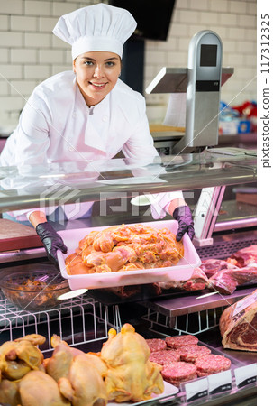 Young woman puts chicken meat in showcase Young woman puts chicken meat in showcase 117312325