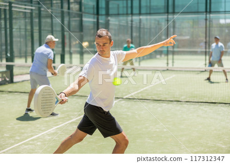 Young and elderly men playing padel against two men Young and elderly men playing padel against two men 117312347