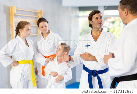 Family in kimono in gym at group training session speaking with their trainer Family in kimono in gym at group training session speaking with their trainer 117312685