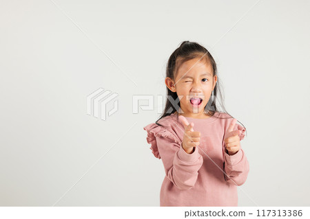 Cheerful Asian young kid girl excitedly makes two gun finger gesture to the camera with a friendly and cheeky expression. Isolated on white background, kindergarten child exudes positivity and joy Cheerful Asian young kid girl excitedly makes two gun finger gesture to the camera with a friendly and cheeky expression. Isolated on white background, kindergarten child exudes positivity and joy 117313386