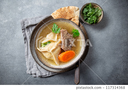 Traditional Jewish Kreplach soup with meat and carrot, gray background 117314368
