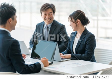 Smiling businessmen and businesswomen having a meeting or business negotiation in a corporate office Smiling businessmen and businesswomen having a meeting or business negotiation in a corporate office 117315742