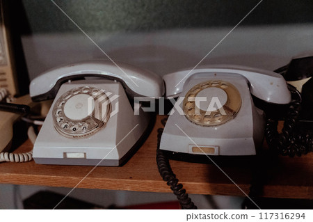 Two vintage rotary telephones sit side by side on a shelf Two vintage rotary telephones sit side by side on a shelf 117316294
