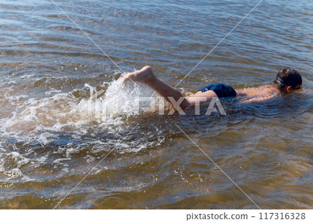 A child is swimming and splashing playfully in a lake 117316328