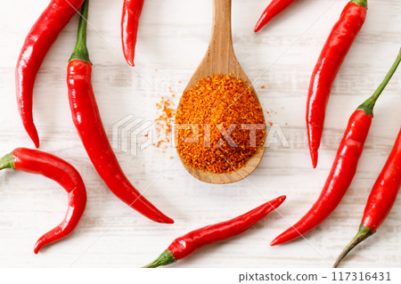 red chilies and ground chilies on white wooden table. red chilies and ground chilies on white wooden table. 117316431