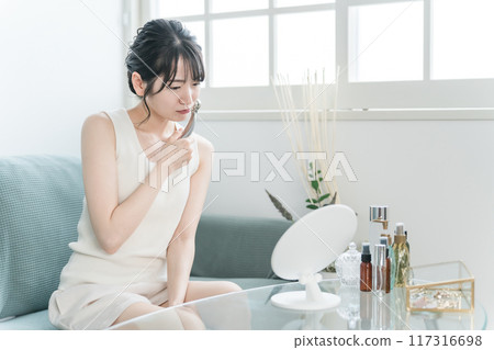 Young Asian woman in room wear massaging with a facial massager (worried / troubled) Young Asian woman in room wear massaging with a facial massager (worried / troubled) 117316698