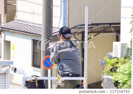 A man attaching a security camera to an outdoor light 117316743