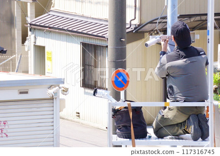 A man attaching a security camera to an outdoor light A man attaching a security camera to an outdoor light 117316745