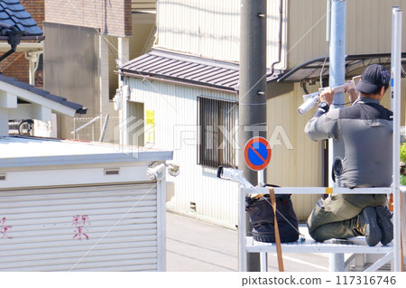 A man attaching a security camera to an outdoor light 117316746