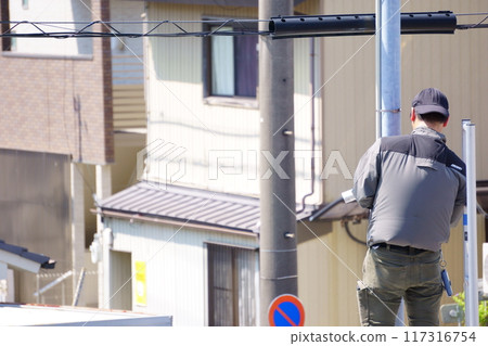 A man attaching a security camera to an outdoor light 117316754