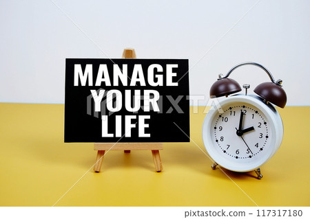 Manage Your Life text on paper card with alarm clock on yellow background Manage Your Life text on paper card with alarm clock on yellow background 117317180
