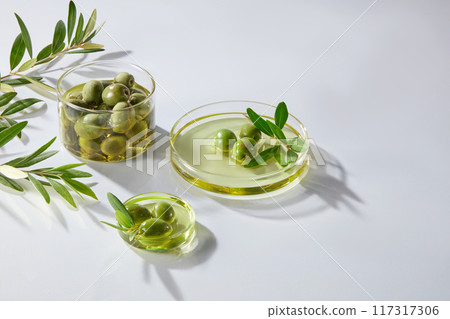 Minimal concept for advertising product of olive extract. Fresh olive, oil and leaves of olives on petri dishes decorated on the white background. Olive oil may offer several health benefits 117317306