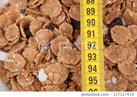 organic cereal in beige bowl with tape measure Diet food. 117317419