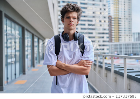 Handsome young man looking at camera outdoors, modern skyscrapers urban style background Handsome young man looking at camera outdoors, modern skyscrapers urban style background 117317695