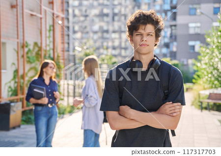 Portrait of college student guy looking at camera outdoor near educational building 117317703
