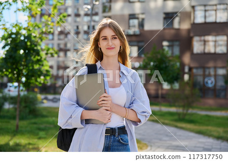 Portrait young female college student holding laptop computer outdoor 117317750