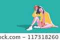 a young woman sitting on the grass, leaning slightly back with one hand holding her red cap 117318260
